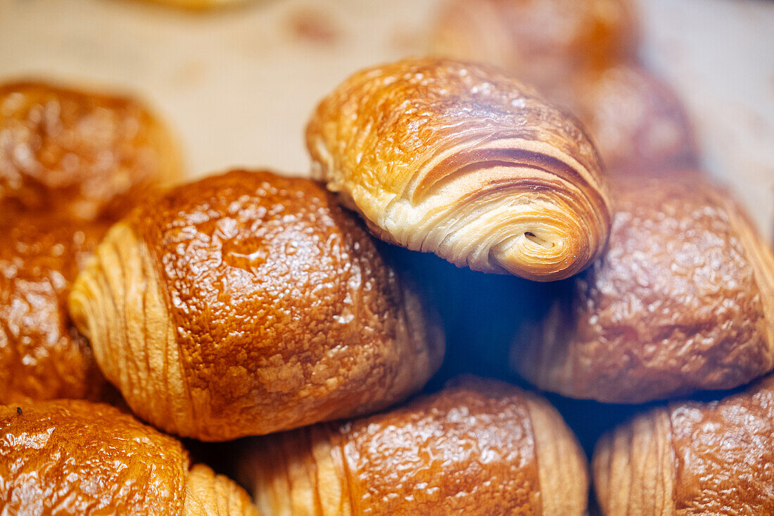 Heap of tasty crispy brown chocolatine placed on parchment in showcase of modern light confectionery with pastry on blurred background