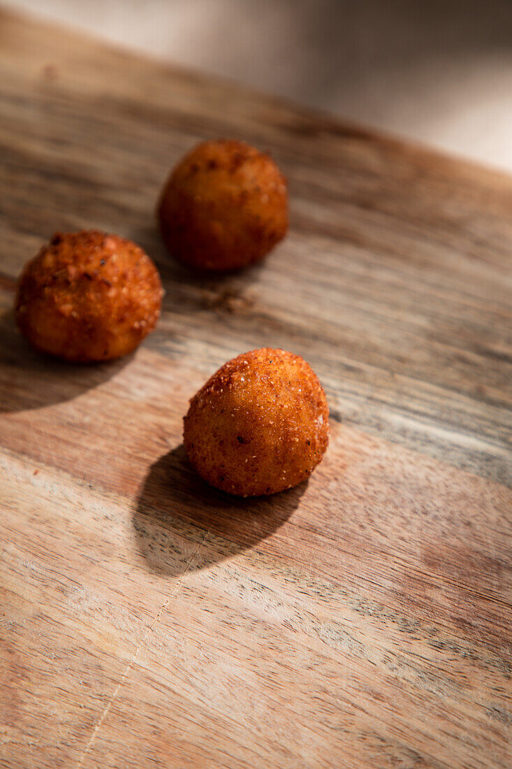 High angle of tasty roasted cheese balls on wooden cutting board in kitchen in ice steam