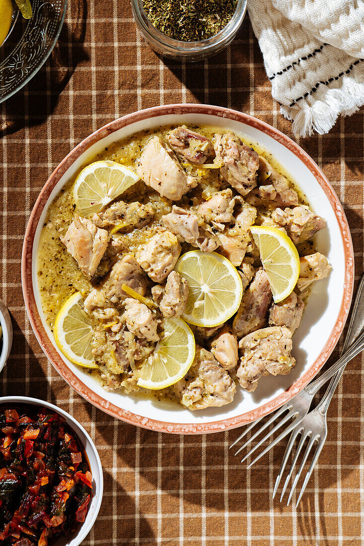 Top view of traditional Greek tasty beef stew with lemon served on table with olives and spices in light kitchen