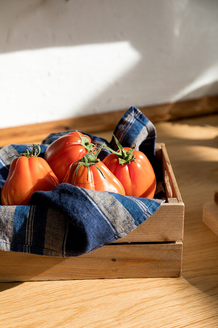 Hohe Winkel von frischen reifen roten Tomaten auf natürlichen Holztablett mit Serviette in der Küche zu Hause platziert