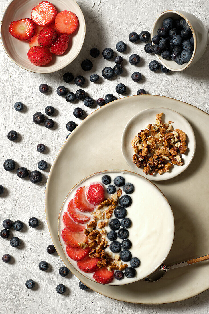 Top view of delicious healthy breakfast bowl with white yogurt and fresh strawberries and blueberries with granola