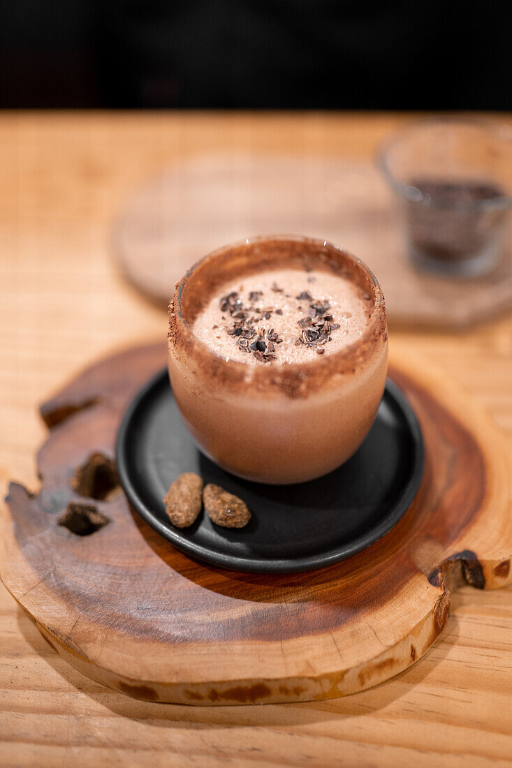 From above glass cup of traditional Mexican Champurrado drink placed on wooden slab on cafe table