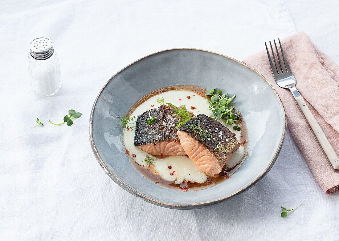 Von oben köstlicher Lachs mit Kartoffelpüree mit grünen Blättern und Gewürzen auf Keramikteller auf Tisch