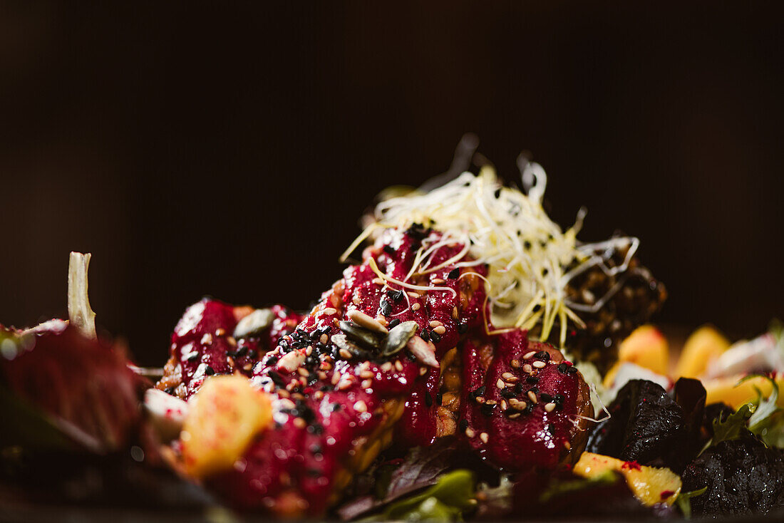 Close up view of plate with tasty vegetarian Indonesian salad with fresh mango and cashew cheese slices near soybeans and condiments covered with basil vinaigrette