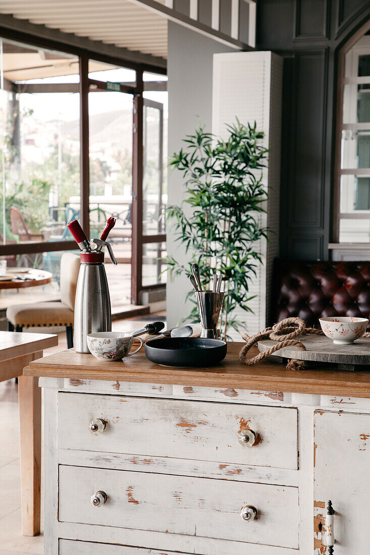 Wooden counter with various kitchenware placed in stylish restaurant with big glass windows in daytime