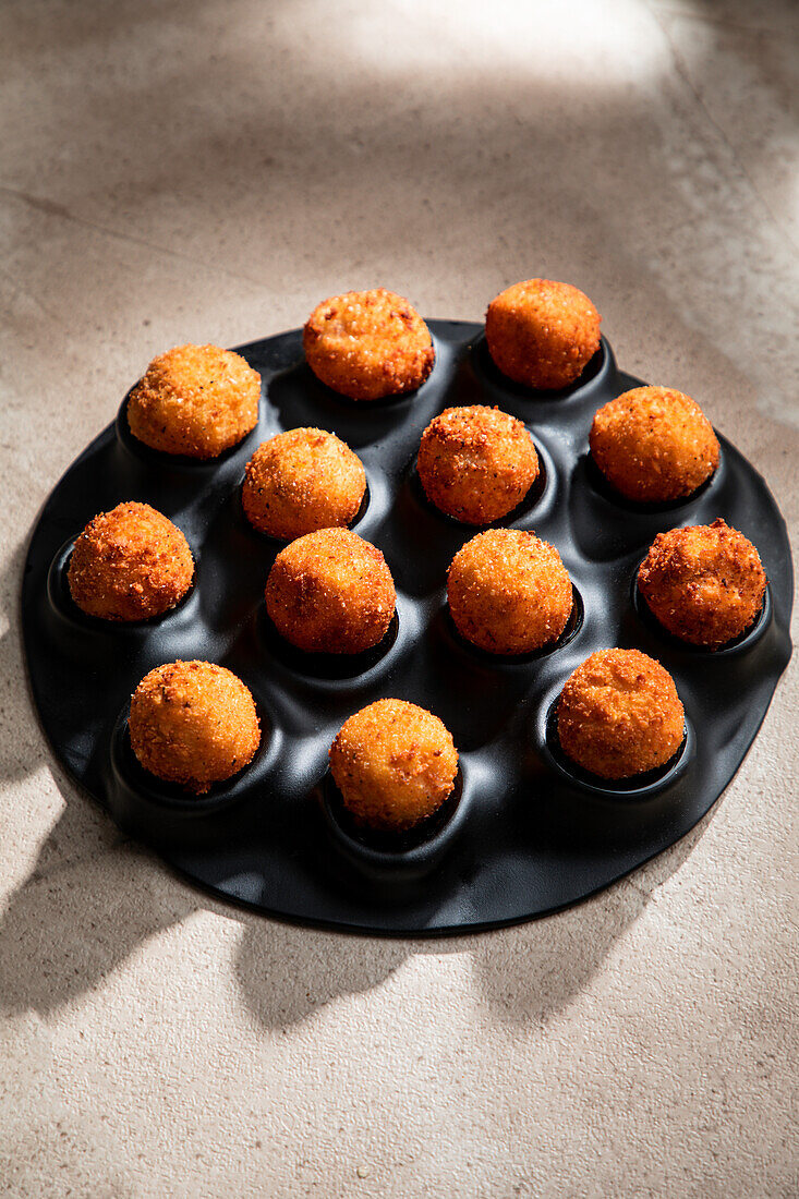 High angle of tasty roasted cheese balls in baking dish on concrete table in the kitchen