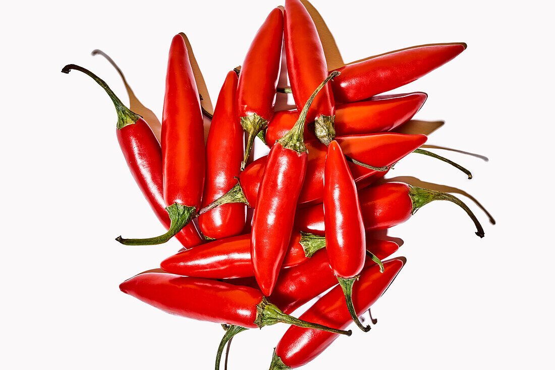 Top view composition with red fresh exotic peppers used as spice or condiment to flavor food on white background