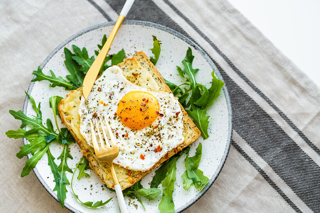 From above toast with eggs and cheese and rocket lettuce served on plate on table background