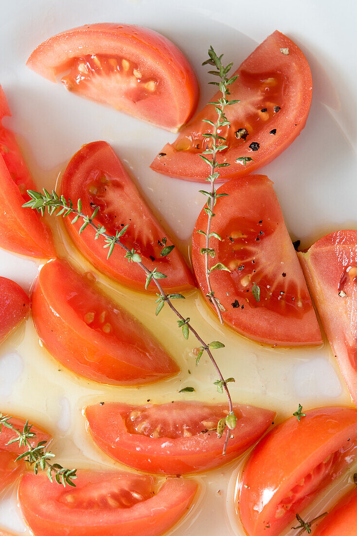 Draufsicht auf appetitliche Tomatenstücke mit grünen Kräutern, serviert auf einem Teller auf dem Tisch