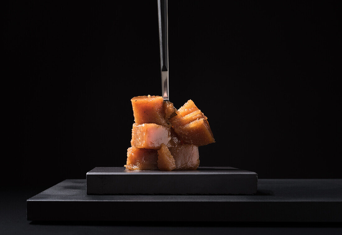 Gourmet quince jelly paste in ceramic plate on black background with fork