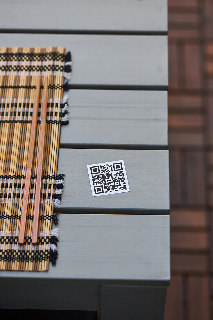 Hochformatiger QR-Code der Speisekarte eines asiatischen Restaurants auf einem Tisch mit Serviette und Stäbchen
