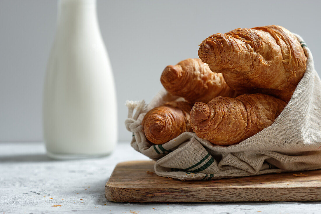 Delicious croissants and bottle of milk placed on table for breakfast in kitchen