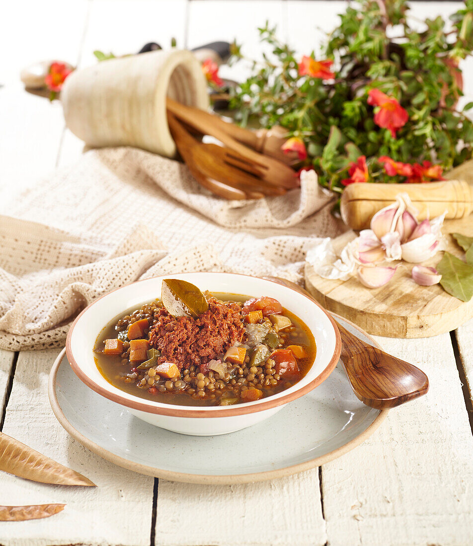 Hoher Winkel von weißer Schale und Teller mit köstlicher Linsensuppe mit Gemüse auf hölzerner Oberfläche in der Nähe des Geschirrs