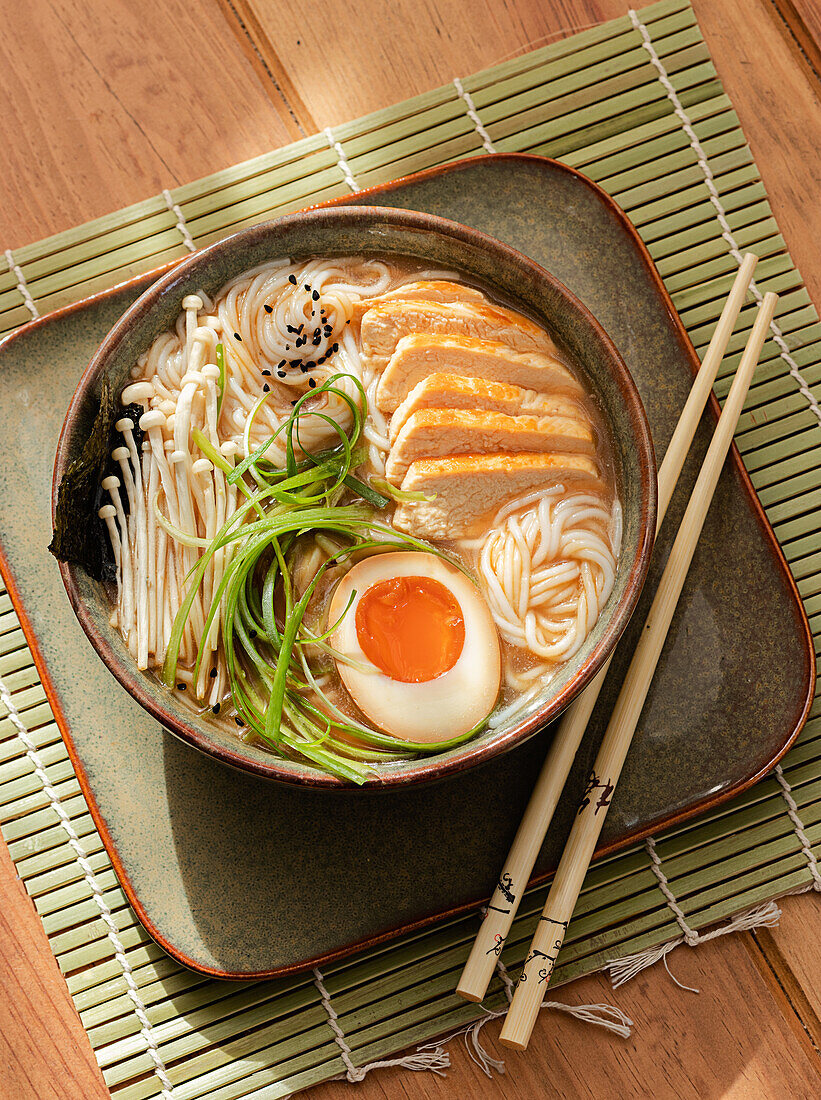 Von oben: Ramen-Hühnersuppe in einer Schüssel mit Stäbchen auf einem Holztisch