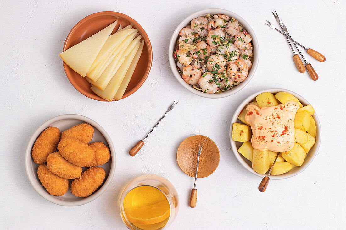 Verschiedene traditionelle spanische Tapas, serviert in Schalen auf einem weißen Tisch von oben