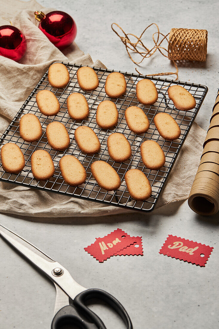 From above of tasty Christmas biscuits placed on metal baking net on table with assorted wrapping supplies