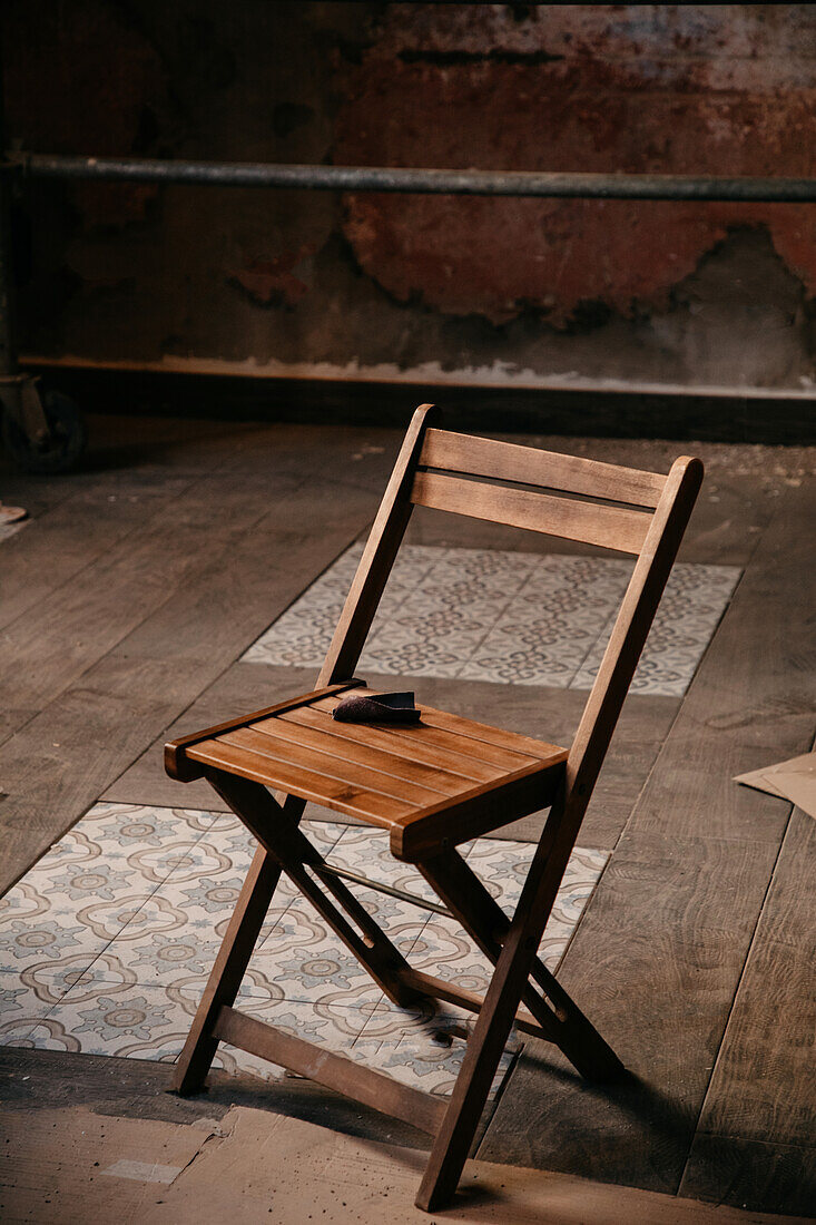 Hoher Winkel eines Stuhls auf staubigem Parkett und Fliesenboden in einem unordentlichen Raum während Reparaturarbeiten