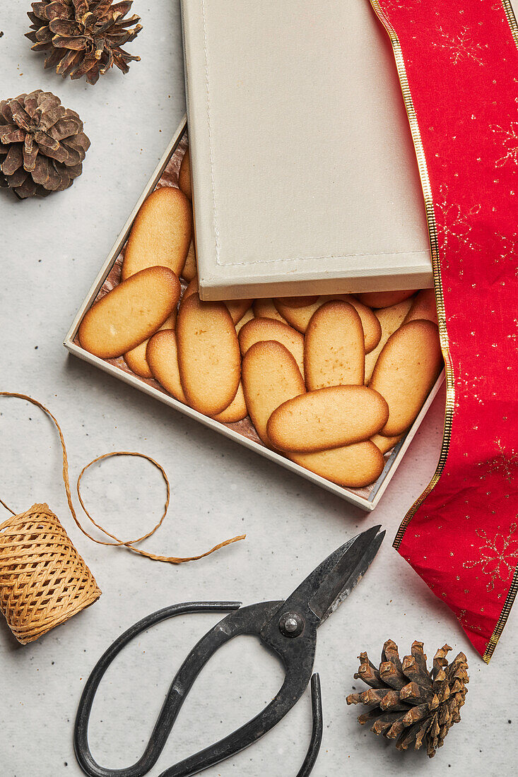 Von oben von leckeren Weihnachtsplätzchen in einer Schachtel auf einem Tisch mit verschiedenen Verpackungsmaterialien