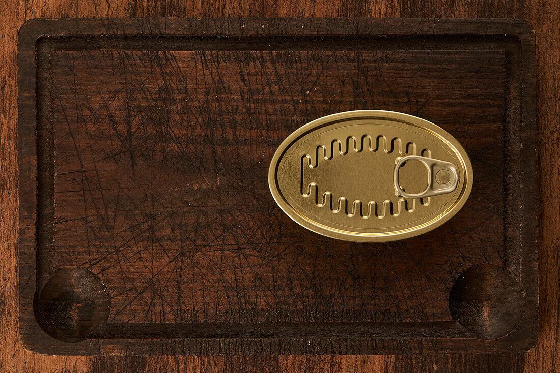 From above scratched chopping board with sealed can with preserved food on rustic lumber table