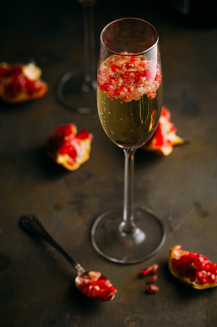 Still life composition of champagne cocktail with pomegranate on a rustic surface