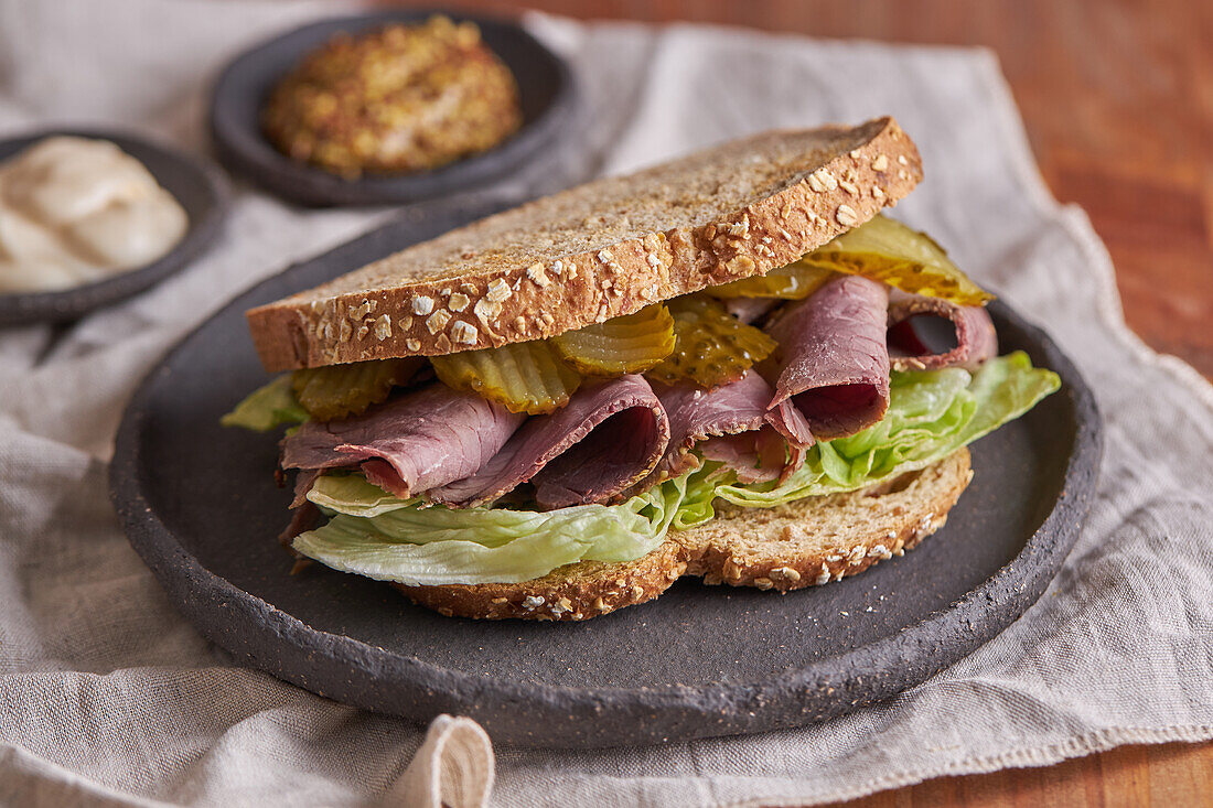 Closeup of a delicious pastrami, lettuce, ham and pickle sandwich