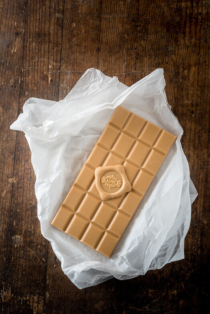 Top view of delicious candy bar with love written of heart on paper on wooden table background