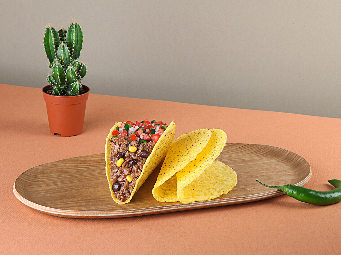 Hackfleisch-Tacos mit Mais und Soße auf einem Holztablett