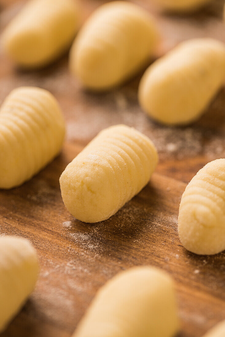 From above top view of uncooked gnocchi placed in organized rows on lumber table during lunch preparation at home