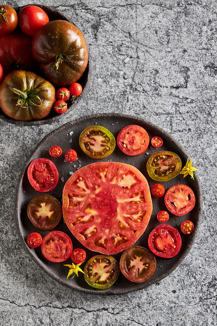 Draufsicht auf köstlich geschnittene Tomaten in einer gusseisernen Platte auf einem Betontisch