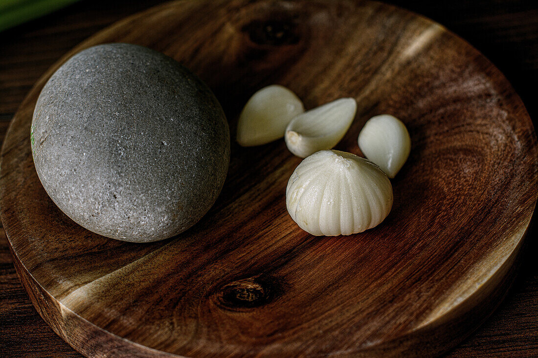 From above of ripe garlic head and cloves placed on wooden mortar with stone on table in kitchen