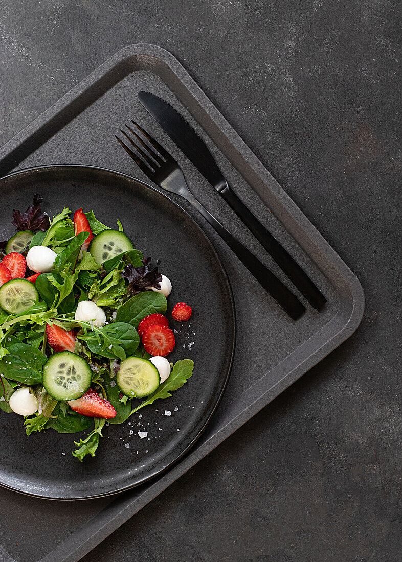 Self-service restaurant with a plate with a summery strawberry and cucumber salad on a tray