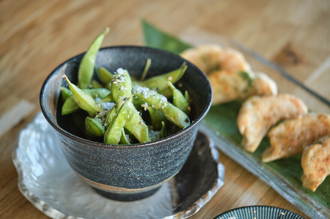 Stockfoto eines köstlichen Tellers mit Sushi und gesalzenen Edamame in einem japanischen Restaurant