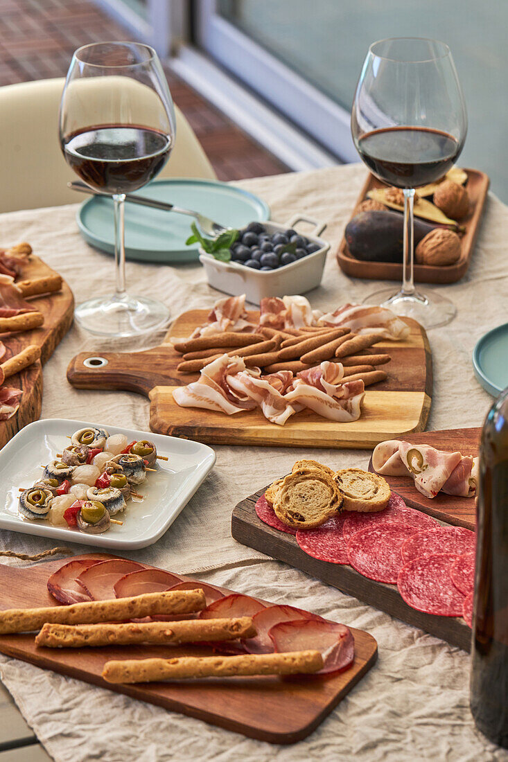 From above of assorted tasty appetizers served on table with tablecloth on terrace