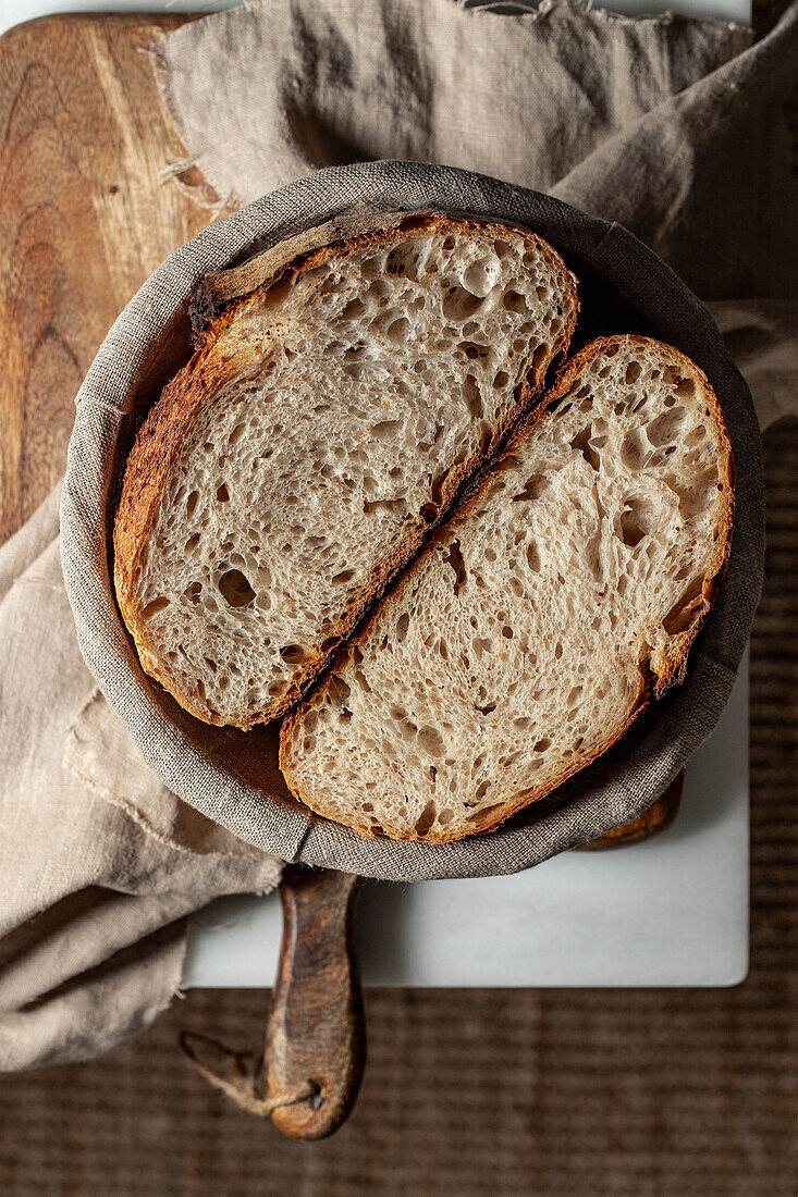 Top view of cut sourdough fresh bread located in plate placed on wooden cutting board