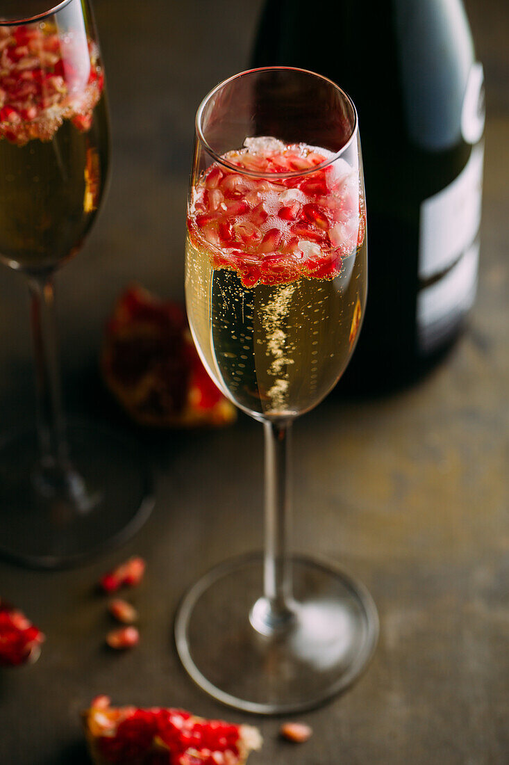 Still life composition of champagne cocktail with pomegranate on a rustic surface