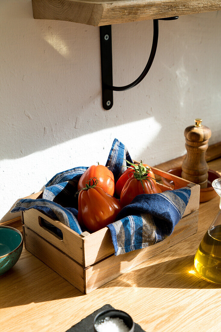 High angle of fresh ripe red tomatoes placed on natural wooden tray with napkin in home kitchen