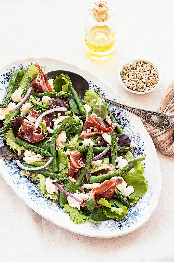 From above delicious prosciutto, mozzarella and asparagus salad on white table background