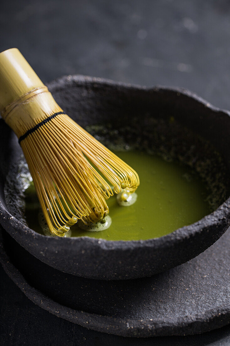 From above of traditional Japanese matcha with tea whisk in stone bowl for traditional oriental ceremony