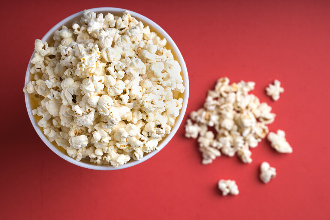 Draufsicht auf eine Schale mit Popcorn auf rotem Hintergrund