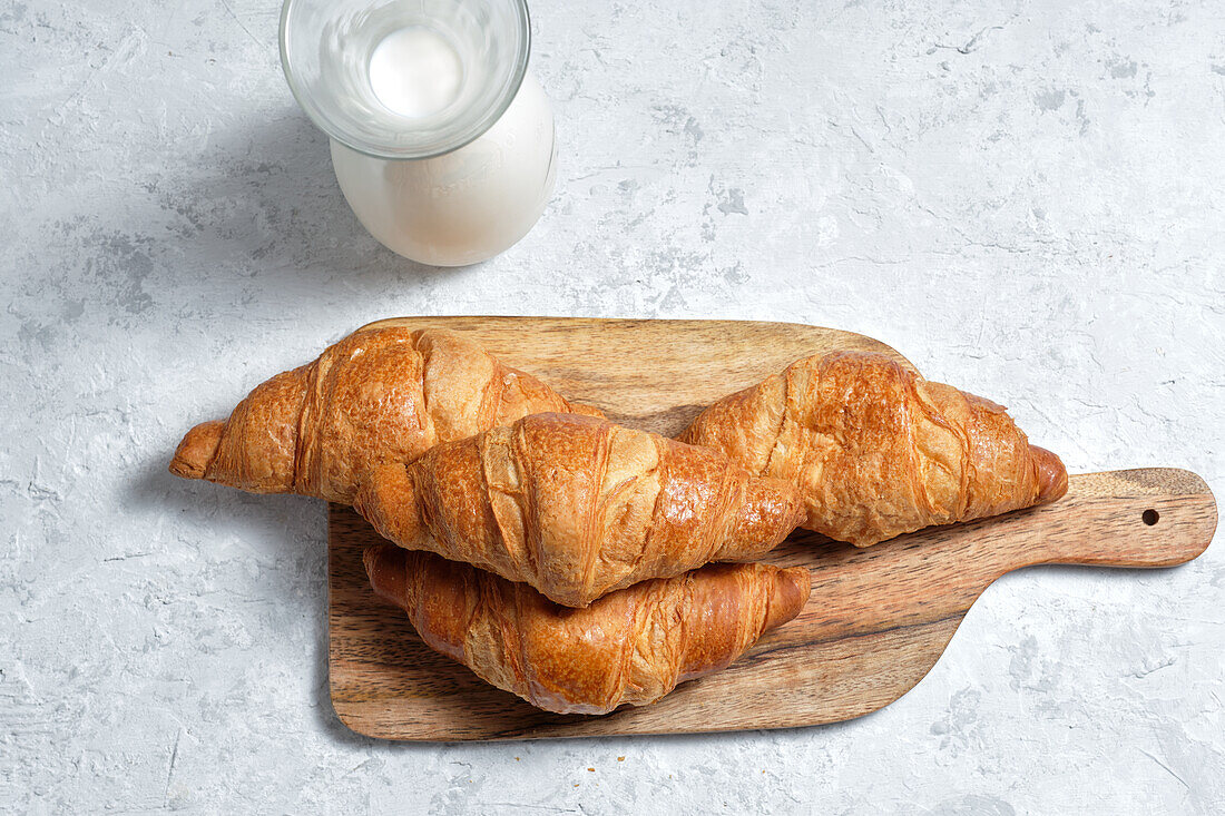 Von oben köstliche Croissants und eine Flasche Milch auf dem Frühstückstisch in der Küche