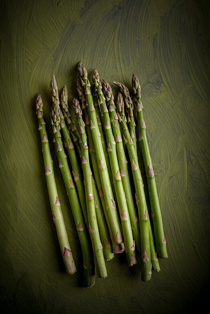 Top view of heap of raw asparagus stalks with uneven surface and wavy edges