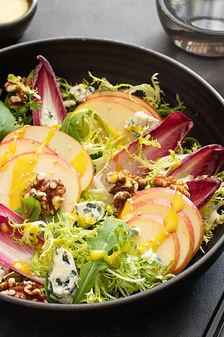 Von oben bunter köstlicher Salat mit Endivien, Apfel und Roquefortkäse auf dunklem Hintergrund