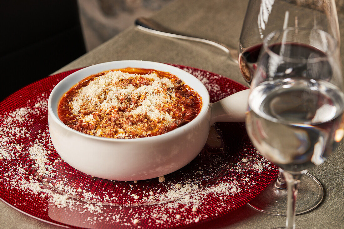 From above delicious eggplant parmesan dish served in ceramic pot near glasses of wine and water during dinner in restaurant