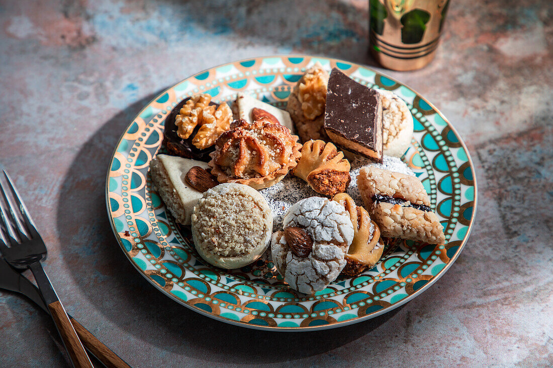 Von oben Baklava und Kekse mit marokkanischem Pfefferminztee neben Messer und Gabel auf einem mit Minzblättern dekorierten Tisch