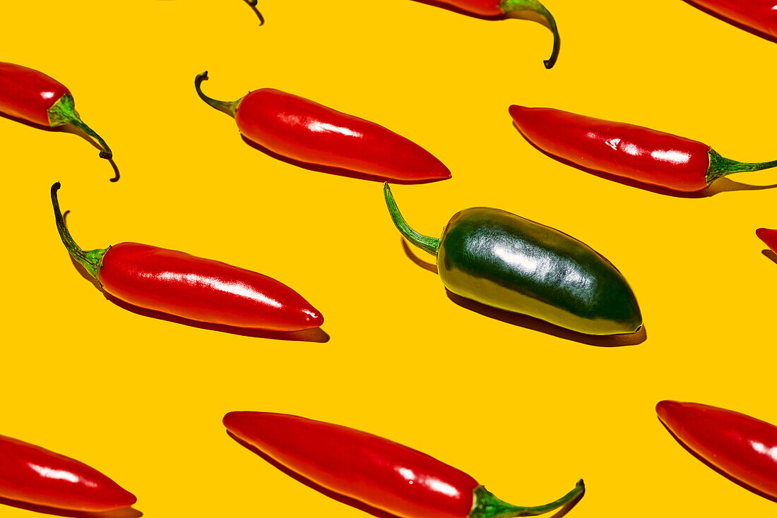 From above of fresh ripe chili peppers with hot green vegetable of different kind on yellow background