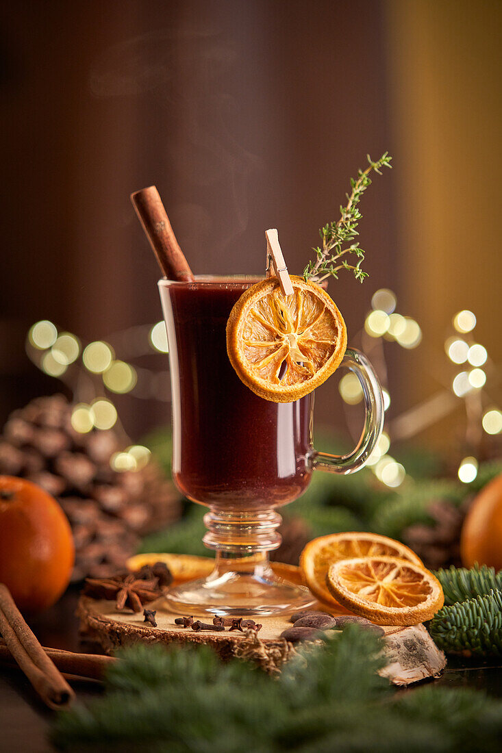 Glühwein oder Weihnachtspunsch, serviert in einem Glasbecher mit getrockneten Orangenscheiben