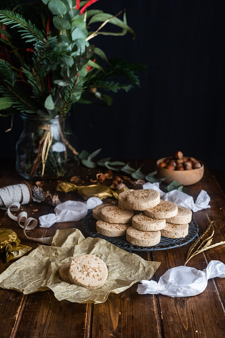 Pile of appetizing sweet shortbread cookies with hazelnuts served on plate on wooden table with festive wrapping paper and ribbons for Christmas celebration