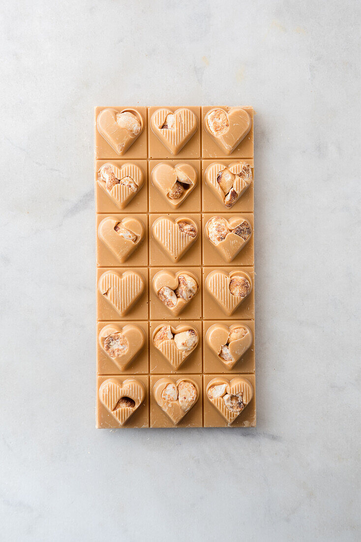 Top view of delicious candies with nuts in shape of heart on marble table background