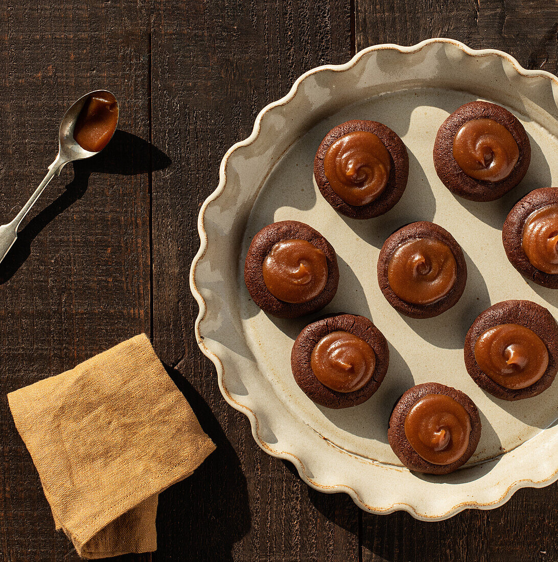 From above salted caramel chocolate cookies on ceramic plate on wooden table background