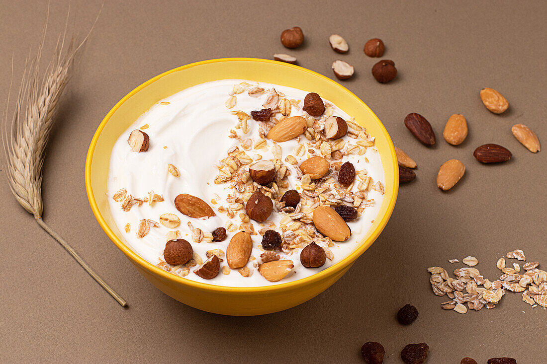 From above yoghurt served with oats and dried nuts on brown background